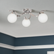 A contemporary semi flush ceiling light with a polished chrome finish, featuring three swirled arms and three matt opal glass spheres.